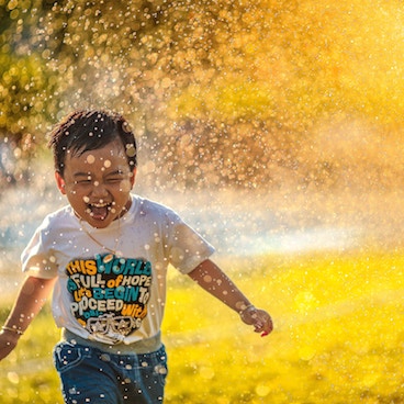 Lachendes Kind unter Wassersprenger